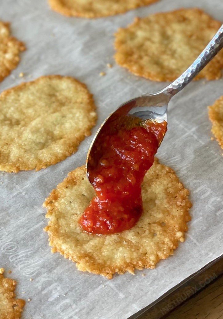 A fun and easy low carb snack idea! Mini pizza crisps made with a parmesan cheese crust. Super fast and simple to make with just cheese, sauce, and pepperoni! Great as a last minute meal or crunchy snack. So yummy!