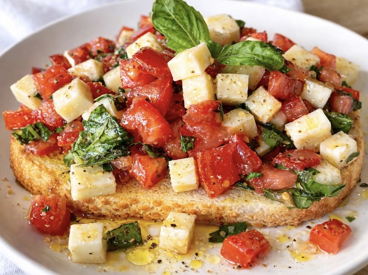 Close up view of delicious caprese toast a vegetarian lunch or dinner made with fresh tomatoes, basil, and mozzarella cheese. 
