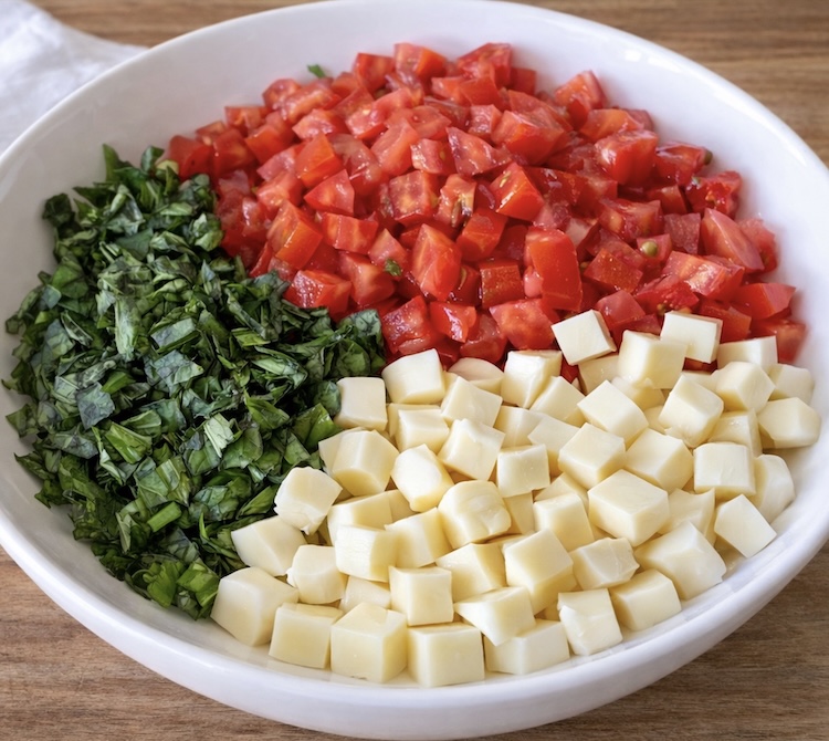 Step 1 How To make Caprese Toast: Chopped mozzarella, tomatoes, and fresh basil in a bowl. 
