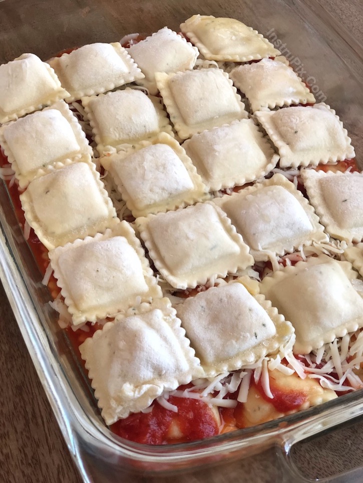 Frozen ravioli layered in a baking dish with marinara sauce and shredded cheese, ready to get baked in the oven until hot and gooey. 