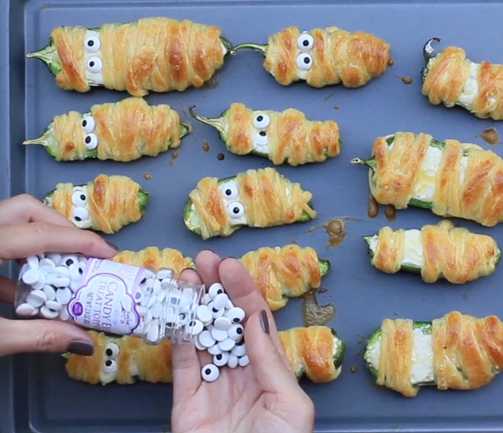 Placing candy eyes onto baked Jalapeno Popper Mummies that have just come out of the oven. 