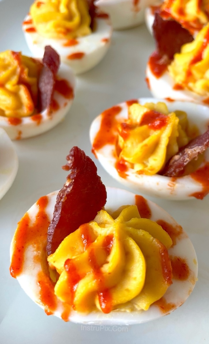 Close up of Chick-fil-A Deviled Eggs, an easy make ahead party appetizer served cold with sriracha sauce and crispy bacon. 
