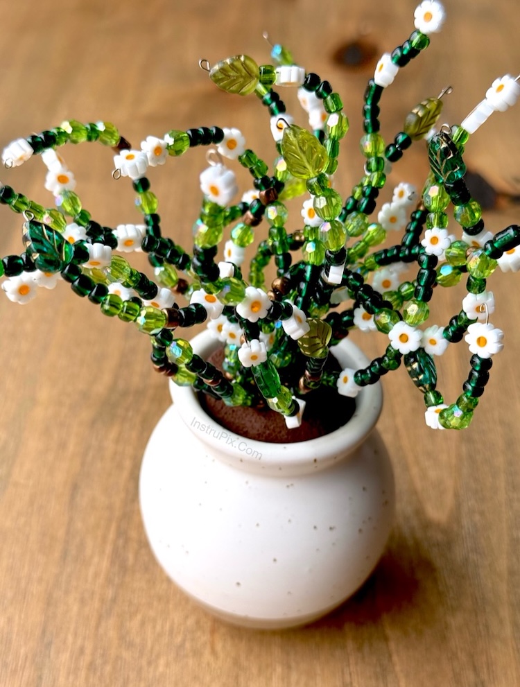 Green beaded vine plant with flowers in a small pot. An adult craft idea and handmade gift.